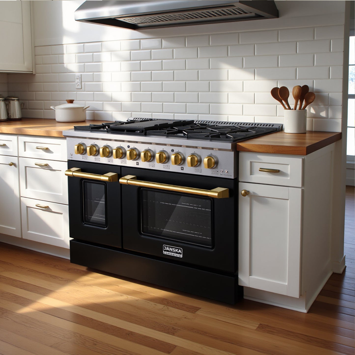 Janska black gas range in 48 inch with gold knobs and handles inset in a white classic kitchen with white cabinets, white subway tile backsplash, wooden floors and rangehood. 