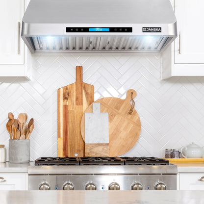 Janska range hood above a stove with wooden cutting boards on the stove. 