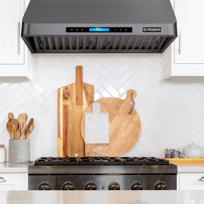 Janska range hood above a stove with wooden cutting boards on the stove. 